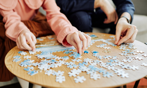 A puzzle being put together by two people.